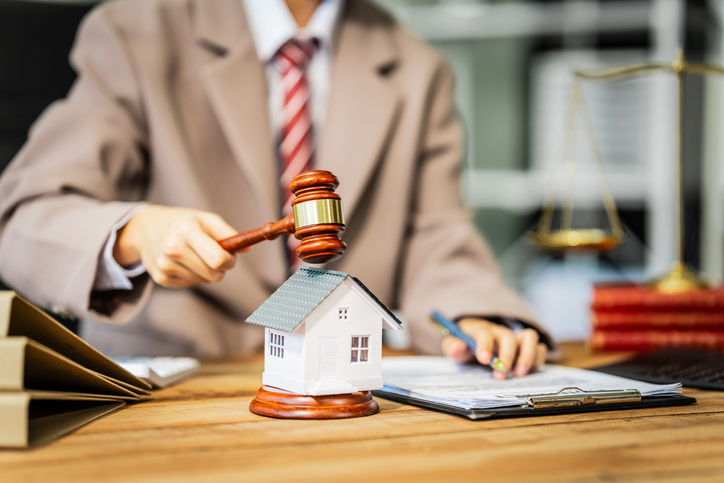 A young businesswoman is working at her desk, reviewing contracts and preparing for litigation, while also managing her responsibilities as a homeowner involved in renovation and real estate.